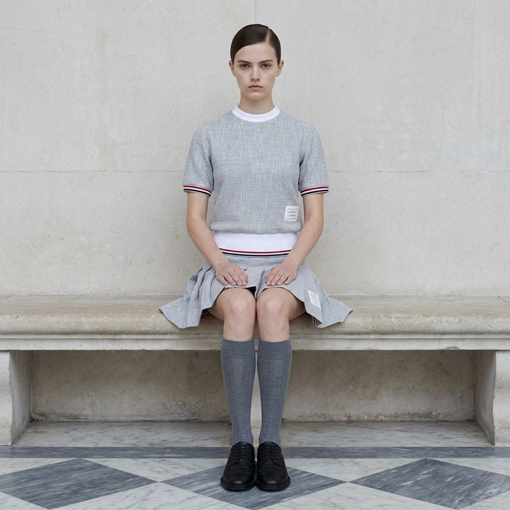Thom Browne heather grey textural knit short sleeve tee with red, white, and blue striped tipping on sleeve cuffs and hem, white ribbed crew neck and hem band, and woven brand label on chest - lifestyle
