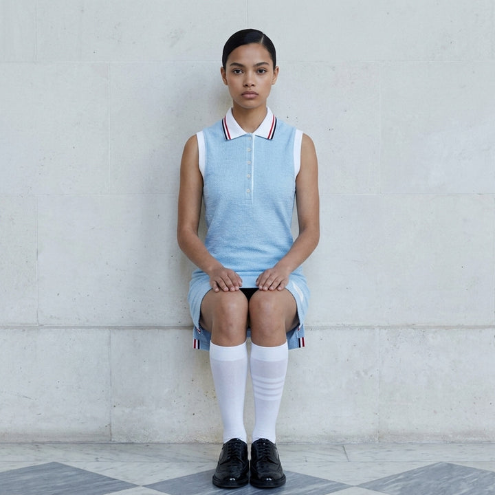 Thom Browne sleeveless polo dress in light blue bouclé with white collar featuring red, white, and blue stripe tipping, button placket, and signature 4-bar stripe at the hem - lifestyle