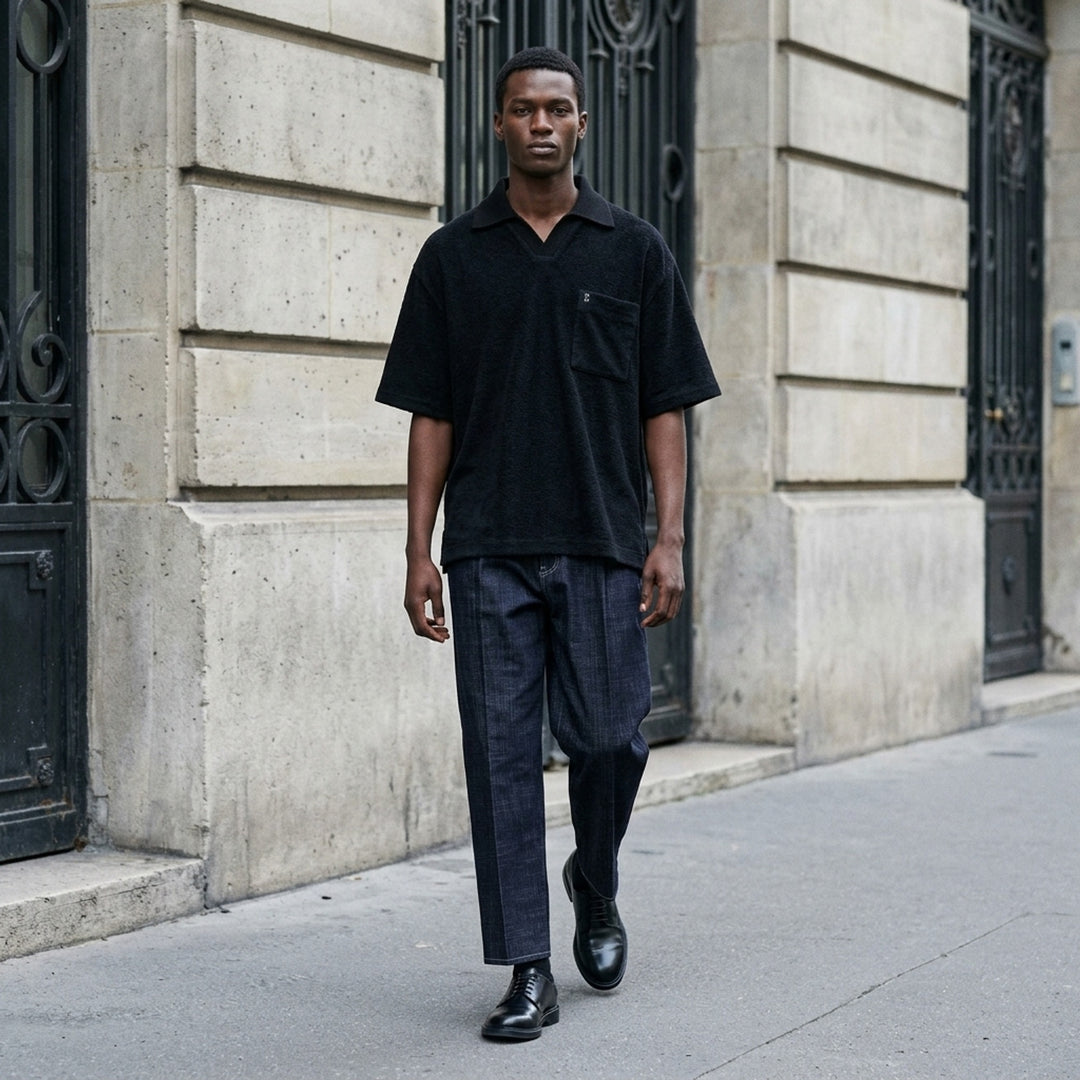 Wooyoungmi Oversized Textured Polo in black, featuring an open-placket collar, boxy short-sleeve silhouette, chest patch pocket with tonal WM monogram badge, and side hem vents - lifestyle